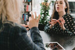 Two women communicating using sign language in a library.
