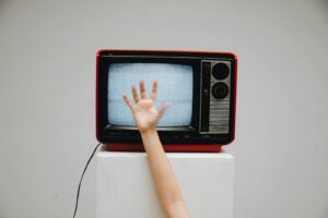 A classic retro television displaying static with a hand reaching towards the screen.