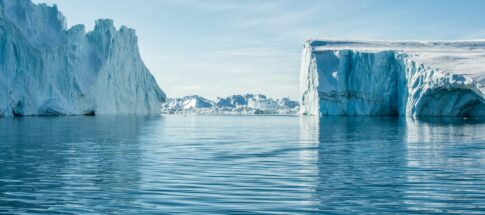 icebergs on body of water under blue and white sky at daytime