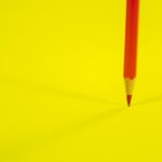 Red Color Pencil on Yellow Background