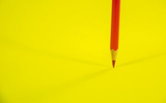 Red Color Pencil on Yellow Background