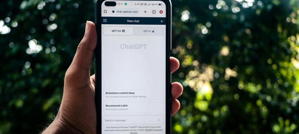 A person uses ChatGPT on a smartphone outdoors, showcasing technology in daily life.